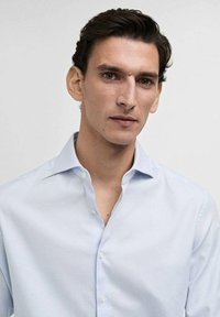 Ljusblå button-up skjorta med subtilt rutmönster, mjukt tyg, spetskrage och långa ärmar. Har en slim fit-design.