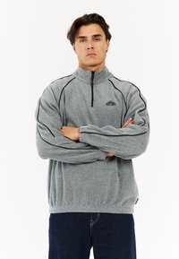 Grau Fleece-Pullover mit hohem Kragen, Halbzipp und schwarzen Akzenten an den Schultern und Ärmeln. Elastischer Saum und Logodetail.