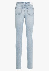 Ljust blå jeans med slim fit, utrustade med två bakfickor och en slät yta. Midjebandet är något förhöjt med en etikett.