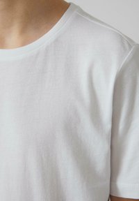 Witte katoenen t-shirt met een zachte textuur, ronde hals, korte mouwen en een fitted vorm. Bevat minimale stikseldetails.