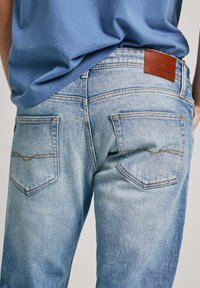 Jeans de mezclilla azul claro con un acabado deslavado, que cuentan con dos bolsillos traseros y un parche de cuero marrón de la marca en la cintura. Corte recto.