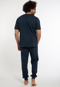 Pigiama in cotone blu navy con top a maniche corte e pantaloni con risvolto. Texture liscia e vestibilità comoda. Il retro è semplice, senza motivi.