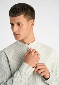 Camisa de rayas verde claro y blanca con cuello mao, cierre de botones y mangas largas. La tela parece suave y ligera.