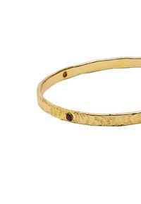 Złota bransoletka o fakturowej powierzchni, z subtelnym akcentem czerwonego kamienia szlachetnego. Smukły, okrągły kształt z młotkowanym wykończeniem.