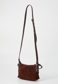 Smeđi sučani crossbody torba s patentnim zatvaračem i podesivim kožnim remenom. Ima srebrni hardver i kompaktni pravokutni oblik.