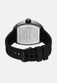 RVS horloge met een rechthoekige wijzerplaat, rubberen band en een geperforeerde achterkant met gegraveerd "POLICE" en een zonnestraal patroon.