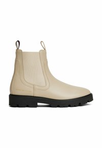 Botas Chelsea beige hechas de material suave, con paneles laterales elásticos, suela de goma negra con surcos y una lengüeta en la parte trasera.