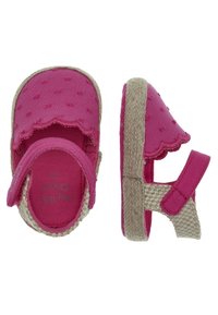 Różowe sandały z tkaniny z falowanymi krawędziami, beżowymi, teksturowanymi podeszwami i regulowanym paskiem. Na górnym materiale znajduje się wzór z wypukłymi kropkami.