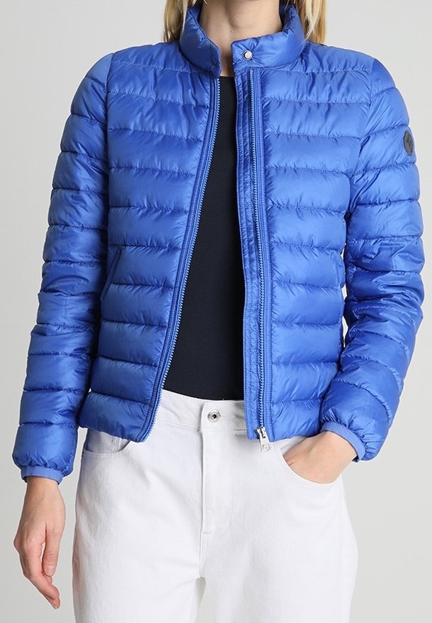 Blå puffjacka i glänsande material, med hög krage, framdragkedja, vertikal quiltning och en rund logo på ärmen.