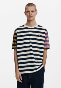 Striped t-shirt featuring navy, white, and mustard colors, with short sleeves in varying shades and a small logo on the chest.