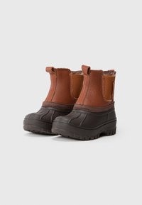 Korte brune læder- og sorte gummistøvler, der er vandtætte med ankelhøjde, pull tabs og kraftige såler med riller.