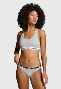 Grauer Baumwoll-Sport-BH mit einem breiten elastischen Band mit schwarzer Markenbeschriftung, kombiniert mit grauen Baumwoll-Thong-Unterhosen und einem nahtlosen Design.