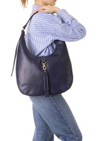 Donkerblauwe leren handtas in hobo-stijl, met zilverkleurige hardware en een gestructureerde schouderband. Kenmerkende stiksels accentueren het ontwerp.