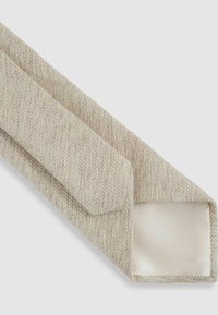 Beige slips med en strukturerad vävd mönster och slät satinfoder. Har vinklad spets och avsmalnande ände för en skräddarsydd look.