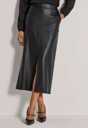 Zwarte leren midi-rok met een split aan de voorkant, een gladde textuur en een aangesloten tailleband. Combinatie met zwarte puntige hakken.