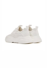 Witte sport sneakers met een gestructureerde mesh bovenkant, gevoerde kraag en dikke zool. Heeft trekhaakjes en subtiele lijnontwerpen aan de zijkanten.