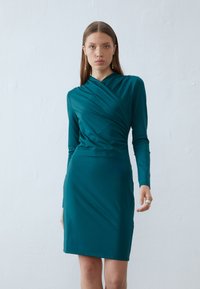 Teal, langermet kjole med drapert halsutringning og tettsittende silhuett. Glatt stoff med en lett glans, knelengde, minimale detaljer.