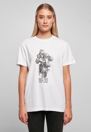 Hvitt bomull T-skjorte med et svart-hvitt blomster grafisk design med teksten "VENT IKKE TIL DET ER FOR SENT" under. Korte ermer.
