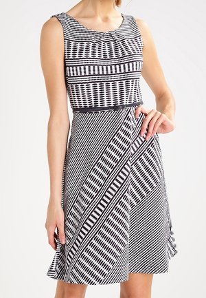 Robe sans manches noire et blanche à motifs, longueur genou, taille cintrée et motifs géométriques variés.