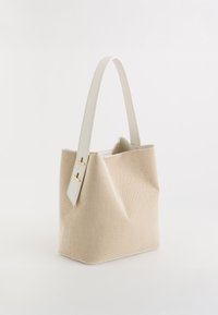 Sac à main en tissu beige avec une forme structurée, poignée en cuir blanc et accents en métal doré. Détails de surface texturée.