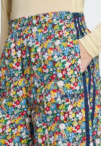 Floral patterned pants featuring a multicolor design on a blue background, with an elastic waistband and side pockets.