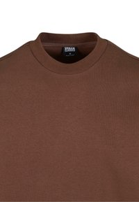 Sudadera de cuello redondo marrón hecha de una tela suave con cuello acanalado y una textura sutil. Etiqueta visible dentro del cuello.