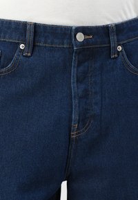 Dark blue denim jeans with a smooth texture, featuring a front button closure, belt loops, and gold stitching along the seams.
