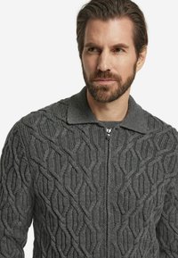 Szary dzianinowy kardigan z zamkiem błyskawicznym z przodu, ozdobiony teksturowanym wzorem w diamenty i płaskim kołnierzem. Materiał wydaje się gruby i ciepły.