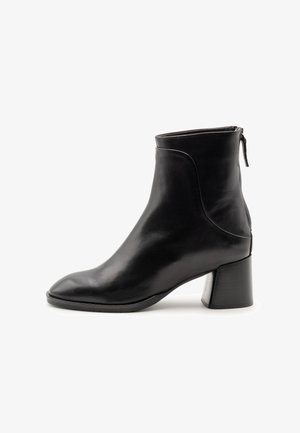 Stivaletto in pelle nera con punta quadrata e tacco chunky. Presenta una cerniera laterale e una texture liscia e lucida con cuciture minime.