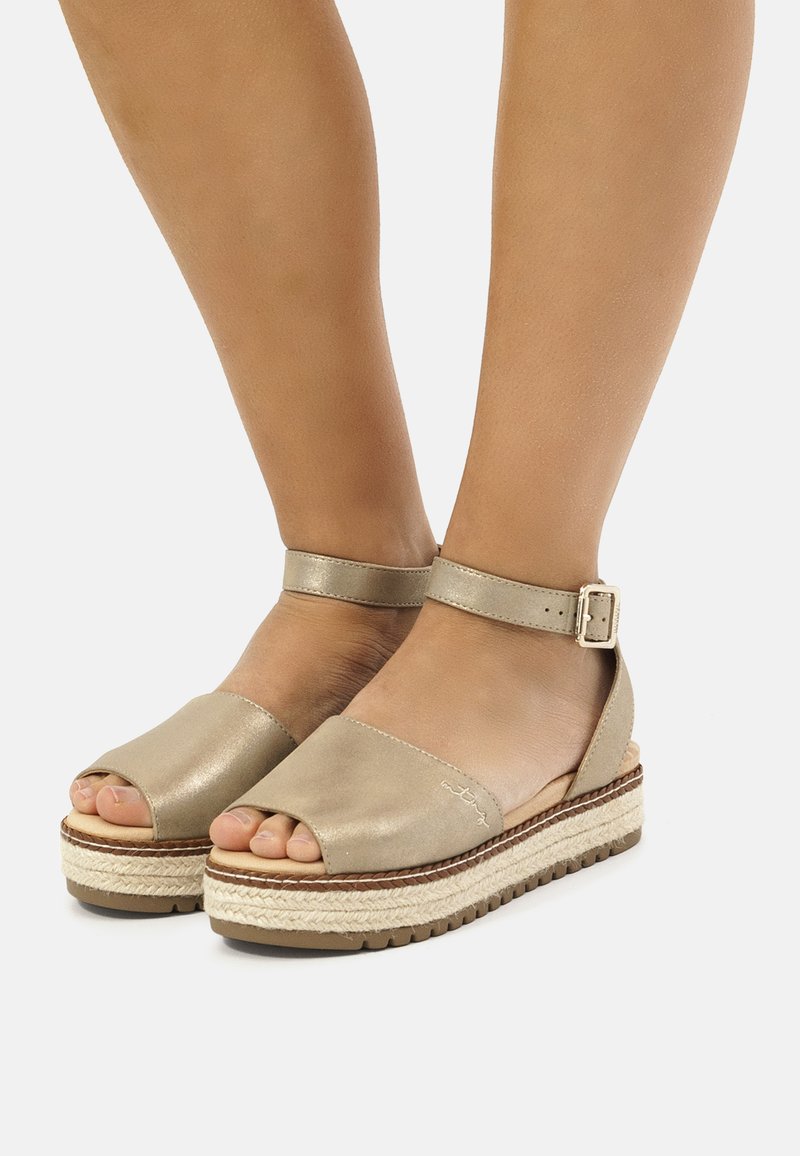 Sandalias de plataforma beige con punta abierta y tira en el tobillo, que cuentan con una entresuela de yute trenzado y un acabado de cuero suave. Detalle de hebilla ajustable.