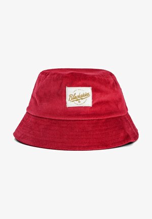 Czerwona czapka typu bucket z szerokim rondem i prostokątną metką z logo "Blackskies" w kolorze złotym z przodu. Miękka tekstura i dobrze ukształtowany kształt.