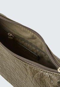 Olivengrüne Lederhandtasche mit strukturierter Oberfläche, ausgestattet mit einem Reißverschluss und einem mit Stoff gefütterten Innenraum. Sichtbarer Reißverschluss und Innentasche.