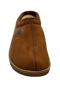 Bruine suède instap pantoffel met een ronde neus, voorzien van een gestikt naad en een ronde logopatch aan de zijkant. Zachte binnenvoering zichtbaar.