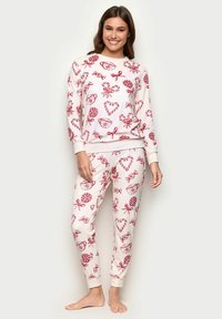 Punainen ja valkoinen pyjama, joka koostuu pitkähihaisesta paidasta ja housuista. Molemmissa osissa on makeisteemainen kuvio. Pehmeä kangas ja rento istuvuus.