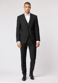 Czarny garnitur z jednopolszowym żakietem, klapami w kształcie notcha i slim-fit spodniami. Zestawiony z białą koszulą i czarnymi butami wizytowymi.