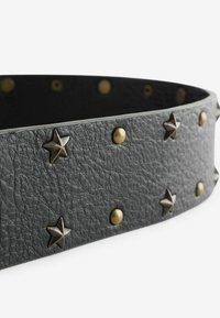 Čierny opasok z textúrovanej kože s striedavými bronzovými kovovými nitmi v tvare hviezdy a okrúhlymi na povrchu.