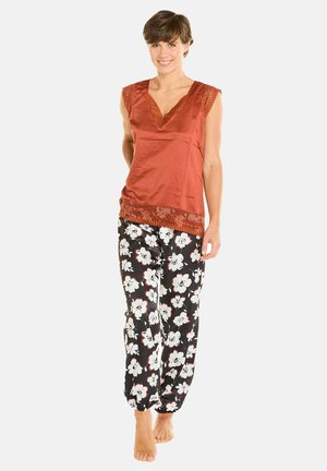 Top sans manches en orange rouillé avec bord en dentelle, associé à un pantalon noir à motifs floraux blancs. Texture lisse, coupe décontractée.