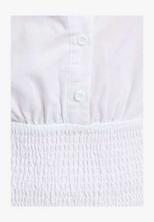 Hvid bluse med knaplukning foran, tekstureret smocket talje og korte ærmer. Materialet virker let og har en blød, glat tekstur.