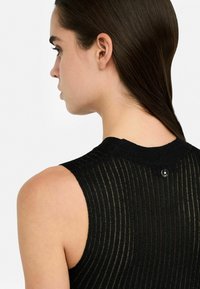 Top senza maniche nero con un design a coste texturizzato, caratterizzato da un collo rotondo e un dettaglio con bottone sul retro.