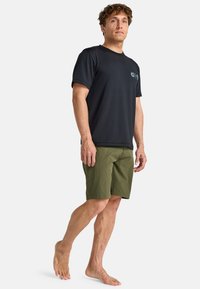 Camisa negra de manga corta con un logo sutil y pantalones cortos verde khaki. El conjunto presenta una tela transpirable y un ajuste relajado.