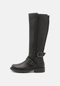 Botas negras hasta la rodilla hechas de un material sintético liso, con punta redondeada, correas con hebillas y una suela texturizada para un mejor agarre.