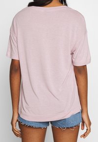 Lichtroze T-shirt met korte mouwen, een relaxte pasvorm en een zachte textuur, gecombineerd met blauwe denim shorts met rafelige zomen.