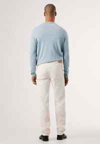 Maglione lavorato a maglia azzurro chiaro, con colletto tondo e maniche lunghe. Abbinato a jeans bianchi e scarpe nere. Tessuto morbido, design casual.