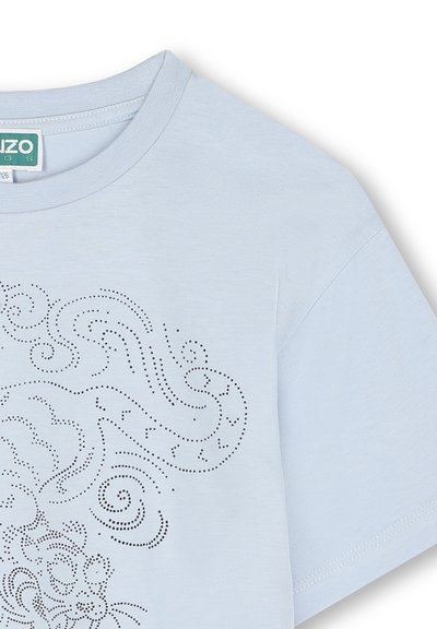 T-shirt en coton bleu clair avec un col rond et des manches courtes, présentant un design graphique à pois avec des tourbillons et des motifs animaliers.