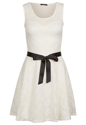 Robe blanche sans manches avec une texture en dentelle, jupe évasée et une ceinture en satin noir nouée à la taille. Encolure arrondie, design longueur genoux.