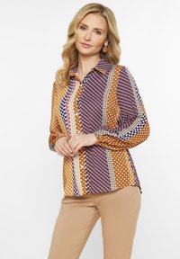 Multifarvet bluse med et ternet og prikket m�ønster i orange, lilla og hvide nuancer. Lange ærmer med manchetter med knap, krave-design.