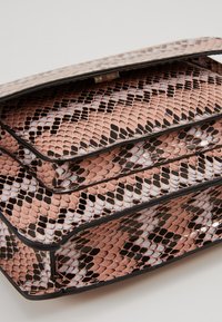 Borsa rettangolare con una stampa serpente lucida rosa, caratterizzata da bordi curvi e un design stratificato. Un bordo nero incornicia la struttura della borsa.