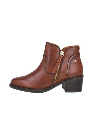 Bota de cuero marrón hasta el tobillo con cremallera lateral, tacón bajo de bloque y punta redondeada, mostrada desde el lado exterior sobre un fondo blanco.
