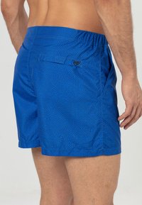 Blauwe zwemshorts met een gestructureerd patroon van zwarte lijnen, elastische tailleband en een enkele achterzak met een klein logo.