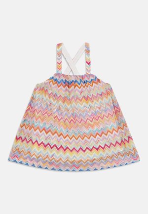 Kolorowa sukienka w wzór jodełki z marszczonym stanem, białymi krzyżującymi się ramiączkami i rozkloszowanym dołem, w żywych odcieniach różu, niebieskiego i żółtego.